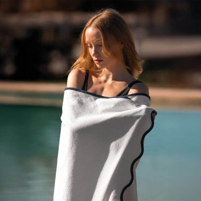 girl wrapped in a beach towel against a pool backdrop