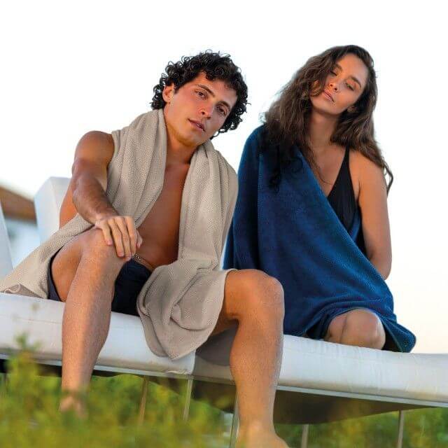 a woman and a man wrapped in beach towels